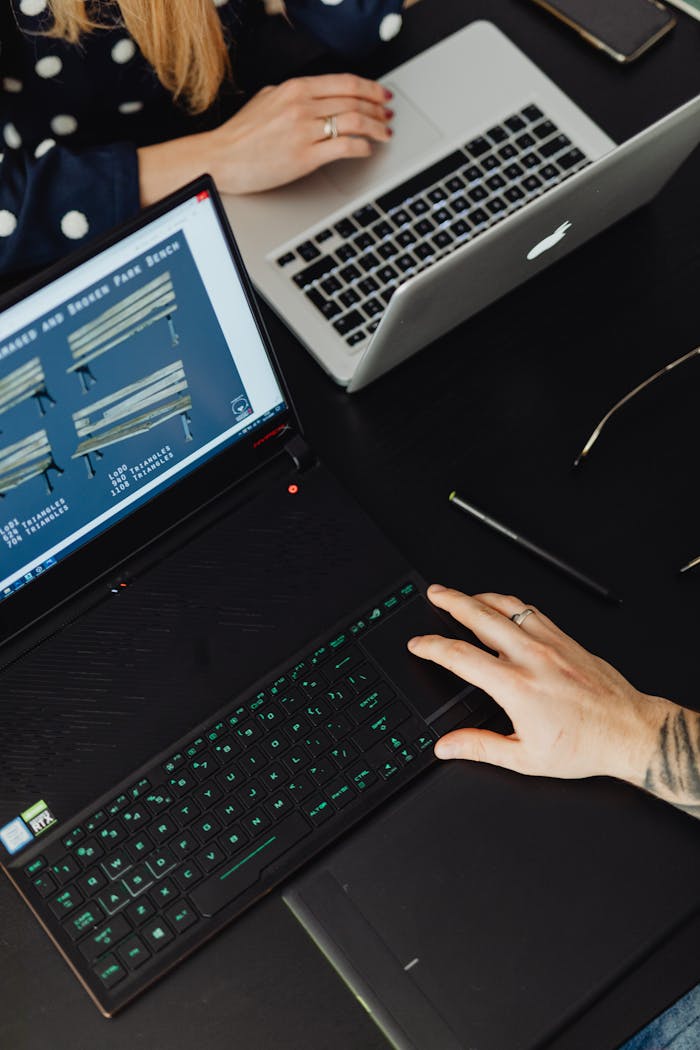 Top view of a collaborative workspace with two laptops and hands engaged in activity.